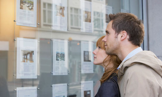 Two people looking at real estate listings on an office window.