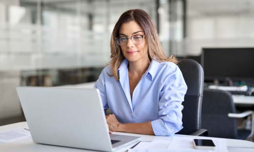 A woman sits at a laptop automating her real estate marketing